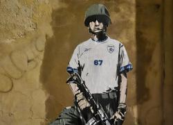 Roma, la nuova opera di Laika "The Bloody Match" contro partita Italia-Israele davanti a sede FIGC: calciatore israeliano con fucile ed elmetto