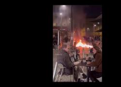 Proteste Francia, coppia al bar chiacchiera mentre la città va a fuoco: immagini paradossali da Bordeaux - VIDEO