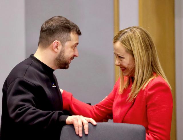 Bruxelles, il guitto Zelensky non si ferma: imbraccia armi e abbraccia la Meloni