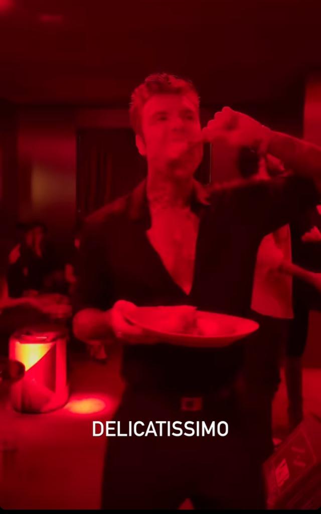 Fedez mentre addenta una bistecca su una pista da ballo